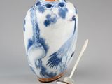 a blue and white vase with a spoon next to it