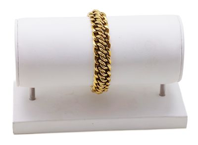 un gros plan d'un bracelet en or posé sur un socle blanc