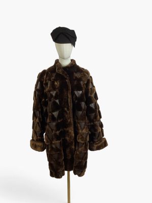 brown fur coat on a mannequin stand with a hat on top