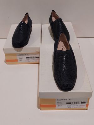 Deux paires de chaussures noires sont posées sur une boîte.