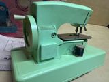 a green sewing machine sitting on a table next to a box