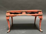 a small red table with two black trays on top of it