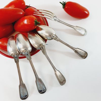 a bowl of spoons and forks with tomatoes on the table