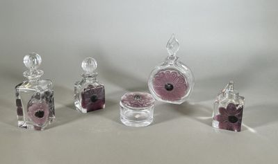 four glass bottles with pink and black flowers in them on a white surface