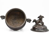 a bronze statue of a dog on a pedestal next to a bowl