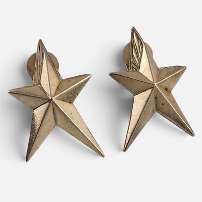 deux boucles d'oreilles en forme d'étoile dorée sur fond blanc