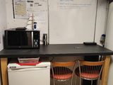 a small kitchen with a refrigerator, microwave, and two chairs