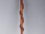 an old wooden walking stick with a twisted handle on a grey background