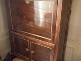 a wooden cabinet with a marble top in the corner of a room