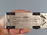 a hand holding a silver and black model of a space ship
