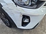 the front of a white car with a dent in it