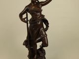an antique bronze statue of a woman with a bird on her arm