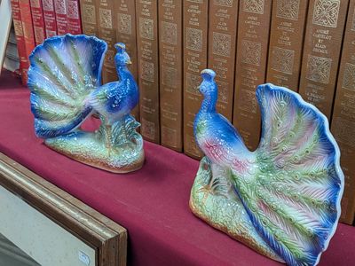 two figurines of peacocks sitting on a red table