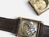 two watches sitting next to each other on a white surface