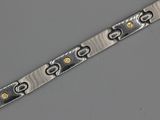 un gros plan d'un bracelet en argent et en or posé sur une surface grise