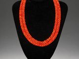 an orange beaded necklace on a black mannequin