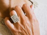 someone is wearing a white sweater and a silver ring on their neck