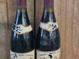 two bottles of wine sitting next to each other on a wooden table