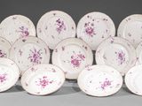 Plusieurs assiettes blanches et roses ornées de fleurs violettes sont empilées les unes sur les autres