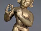 gold figurine of a man holding a bird in his hand
