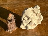 une statue représentant un vieil homme assis près d'un rocher