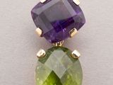 a close up of a green and purple stone pendant on a white surface