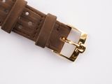 the brown leather watch strap has gold buckles on it