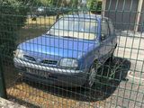une voiture bleue garée derrière une clôture