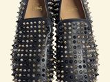 pair of black leather shoes with spikes on them against a white background