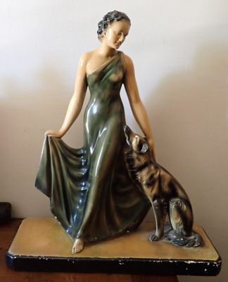 une statue représentant une femme et un chien posée sur une table