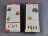 two boxes of barbie dolls sitting on top of a table