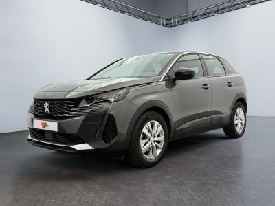Une voiture grise est garée dans une grande pièce aux murs blancs.