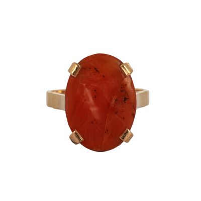 un gros plan d'une bague en pierre rouge sur fond blanc