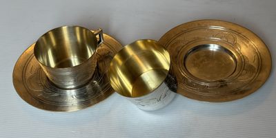 deux tasses et soucoupes en argent posées sur une surface blanche