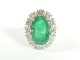 a close up of a green emerald and diamond ring on a white background