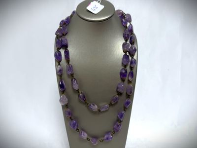 a close up of a necklace with purple beads on a mannequin