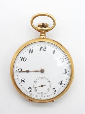 gros plan d'une montre de poche en or sur une surface blanche