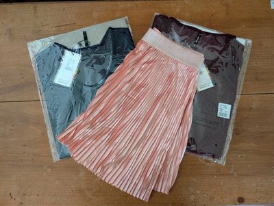 trois paires de jupes pour femmes posées sur une surface en bois