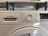 une machine à laver blanche posée sur une étagère dans une pièce