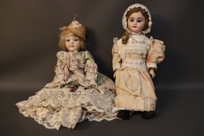 pair of antique dolls sitting next to each other on a black background