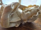 a statue of a woman laying down on a wooden table