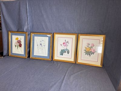 trois photos encadrées représentant des fleurs sont posées sur un canapé devant un rideau bleu