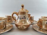 five cups and saucers on a table with a teapot