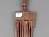 a small wooden comb with a wooden handle on a gray surface