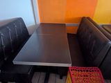 des tables et des bancs dans un restaurant, avec un mur coloré en arrière-plan