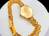 a gold watch with a chain around it on a white plate