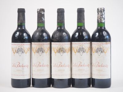 quatre bouteilles de vin rouge sont alignées sur une surface blanche