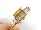 a person holding a gold and blue watch in their hand