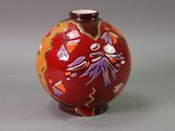 a red vase with a floral design on it