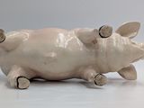 a ceramic pig that is laying down on the ground
